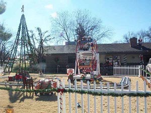The large decorations include a sleigh surrounded by a railroad train and a white picket fence, all adorned and lit for the holiday