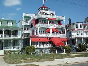 A colorful four story hotel in Cape May, New Jersey, with red awnings and a red-roofed gazebo on top.