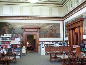 The large high-ceilinged reading room on the second floor has murals on the walls and windows set high above the reading tables.