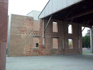 Merely the red brick walls remain, patched in places, and with holes where timbers once rested; a steel roof has been erected to protect the ruins.