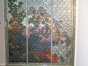 The mural is created in a tiled recess out of interlocking septagonal tiles, separately fired in beautiful colors to create a scene suggesting a tree against a bright sky