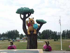 Pooh sits in a fake tree, holding a blue honey pot
