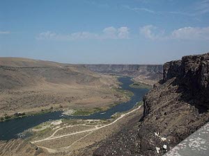 Deep in the wide canyon, flanked by dark brown cliffs, the Snake River winds through a bird refuge especially for raptors