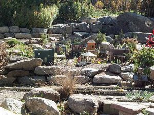 Looking like a rock garden, with desert buildings surrounding the tracks, colored orange and terra cotta and green, the model train disply would be attractive when it is running