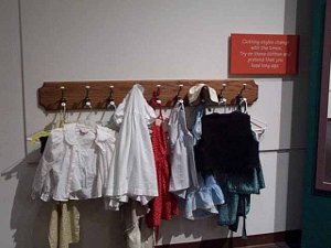 Hanging from pegs on the wall are costumes for children to wear pretending to be early New Mexicans
