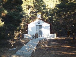 I=The memorial is in a plain white building resembling a chapel, nestled in the woods.