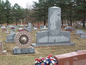 One monument is in the shape of a large circus wagon wheel; another, which stands a good six feet tall, has an engraving of an elephant standing on a small ring on two feet, and a huge circus tent, all on a grey granite tombstone.