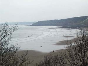 A long sandy beach is the big attraction of Scarborough; in the distance the sand is supplanted by a rocky coast