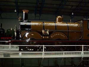 The Gladstone steam locomotive is painted glistening brown and black.  It is displayed inside.