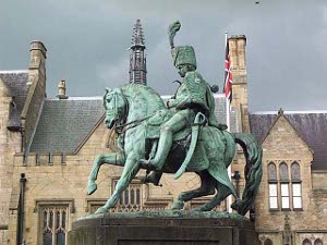 Wearing a beaver hat with a tall plume, this greenish bronze statue shows the general mounted, his sabre at his side, on a high pedestal, against a background of lovely tan stone buildings in Durham.