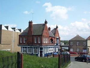 A large two story red brick building, probably an old station, has been remodelled as a pub, the downstairs a bright blue with white trim around all the windows