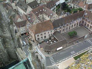 From the top of the tower, the streets of Chartres appear tiny and the pedestrians as small as ants.  The buildings are of a light tan with brown slanting roofs