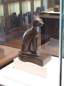 A graceful cat, sitting erect with long front legs, carved in bronze in Ancient Egypt
