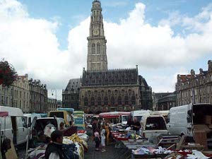 Cars and vans park and out come display tables and merchandise to make an instant market in the Arras square