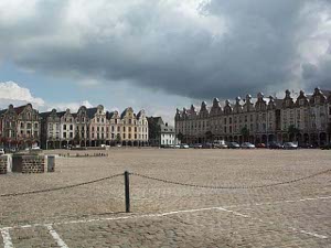 A large square paved with cobblestones and surrounded by four-story 19th century buildings