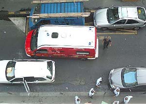 Six cops, one fireman, and the ambulance are visible on the street below; the combatants are carefully separated
