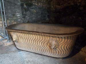 The bathtub has wavy lines and lions carved in the sides