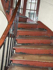 Narrow wooden spiral staircase with iron railing