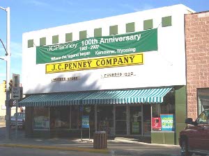 A banner celebrating the 100th anniversary of J. C. Penney Company is posted on the first store in Kemmerer Wyoming.  A green and white awning extends to shade the windows.