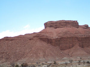 The massive red mountain is silhouetted against a light blue sky