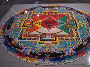 The circular mandala is dazzling and intricately designed, in a rainbow of colors, painstakingly created with colored sand.