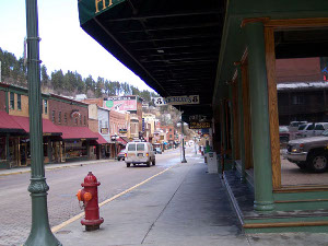 The main street, with hills in the background, is lined with green, red, and brown buildings.