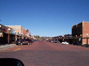 Paved in dark red, the main street of Oberlin, Kansas is wide, flanked by a long line of white lighting globes on each side, with one- and two-story stores and businesses, and plenty of room for angle parking on each side of the street.