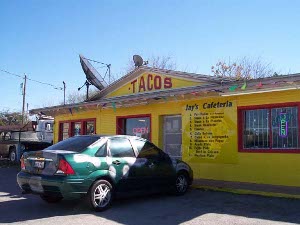 A bright yellow building with red trim and the menu painted on the outside wall, Jay's Cafeteria features few cars, for most of the business is takeout.