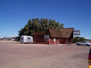 One car, and one old airstream trailer, are all that are parked next to the Bagdad Cafe, a red frame building with a shake roof, a huge tamarisk tree in the back and a hand lettered sign attached to the wall