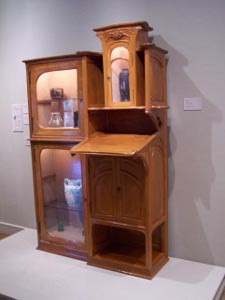 The left hand side of the polished wooden secretary consists of two glass-doored display cabinets