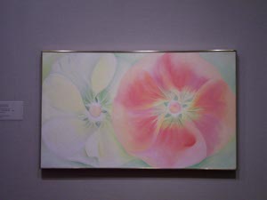 The Georgia O'Keeffe painting features two flowers side by side, one white, one red, with luscious and delicately colored detail at the hearts of the flowers.