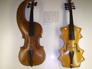 One violin has a curved neck to alter the sounding space; the other, 
in blond wood, has points as if two nonagons were joined together.