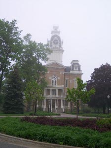 Four story brick building with a tall white wooden clock tower, and white pillars in front of the Hillsdale College Administration Building