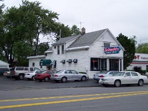 An old white house with a grey shingle roof and green and white awnings over the side, Schwabl's sits unpretentiously with a small parking lot, always crowded at lunch, and an old-fashioned neon sign in front