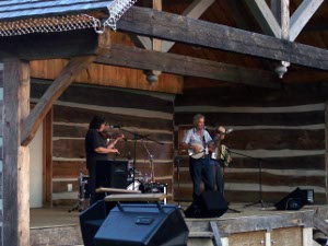 a guitarist, fiddler, and accordionist entertain in the rustic log Bancroft Bandshell