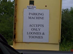 Taped to the yellow parking box is a sign printed by a computer in all caps, reading: 'PARKING MACHINE ACCEPTS ONLY LOONIES & TOONIES'