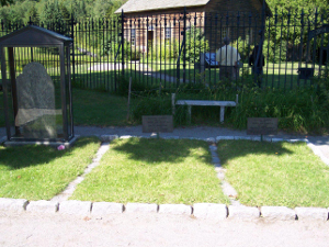 three graves and the old gravestone protected in a glass case