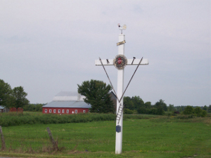 white cross about 12 feet high with decorations and emblems to protect travelers