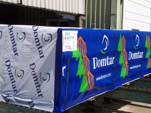 Wrapped in protective plastic with a green tree against a blue background, Domtar two-by-fours will be shipped to a home builder