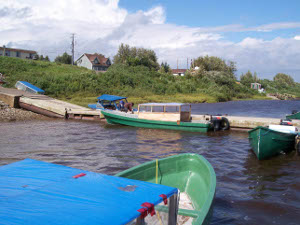 Small green boats with large outboard motors work as water taxis to Moose Factory, which is on an island