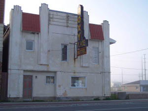 The outside of the motel looks dingy, with a For Sale sign
