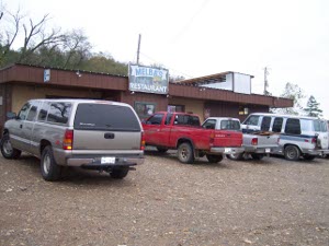 Melba's Restaurant, Norman, Arkansas; a one-story plain brown building with an overhang and four trucks (including ours) parked in front