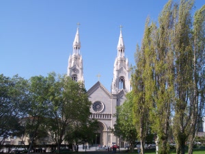 Two tall ornate spires cap the church which the Dimaggio brothers attended; in front of the church is a park with tall trees