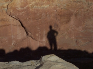 Bob's black shadow against a reddish brown Utah cliff