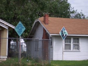 The art project sign by a white wooden house in Amarillo, Texas reads, Who knows how long I have loved you, on a blue diamond background