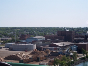 Piles of lumber and sawdust, large buildings and tanks make up the Sault Ste. Marie sawmill.