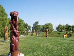 A variety of wooden sculptures surrounded by grass and trees