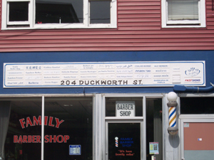 The barber shop at 204 Duckworth Street in St. John's is on the first floor of a red clapboard building with white windows, with apartments above.  An old fashioned barber pole is mounted near the door, and the sign says 'barber shop' in 31 different langauages, reflecting the large varieties of seamen who enter the harbor.