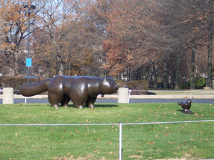 On the lawn in front of the Museum of Fine Arts, a large brown cat
sculpture gazes intently at a small brown bird sculpture, both in polished bronze