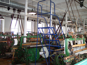 The workroom is painted white, and long axles with pulleys drive
belts which poser the looms, painted green and brown, kept operating with
cloth in process